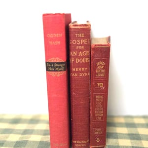 May include: Three vintage books with red covers are displayed. The titles include "I'm a Stranger Here Myself" by Ogden Nash, "The Gospel for an Age of Doubt" by Henry Van Dyke, and "Audels New Electric Library". The books are arranged vertically.