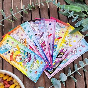 Peut inclure: Un ensemble de dix marque-pages colorés représentant une illustration de boîte de céréales avec un chat sur le devant. Les marque-pages sont disposés en éventail et présentent un dégradé arc-en-ciel.