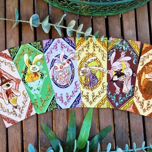 Può includere: Set di sei carte illustrate con personaggi di animali fantasiosi con bordi floreali intricati. Ogni carta presenta un animale diverso, tra cui un coniglio, una falena, una volpe e un gatto. Le carte sono stampate su cartoncino di alta qualità e sono perfette per aggiungere un tocco di fantasia a qualsiasi occasione.