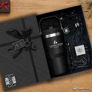 以下が含まれることがあります： ハンドル付きの黒いタンブラー（YOUR LOGO HEREの文字入り）、黒いペン、白い電源アダプター（YOUR LOGO HEREの文字入り）、黒い充電ケーブルが入った黒いギフトボックス。箱の蓋には黒いリボンとギフトタグが付いています。