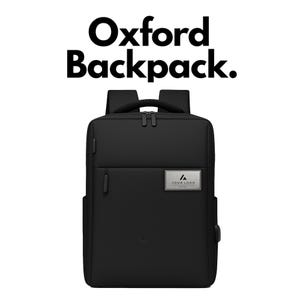 Op de afbeelding: Een zwarte rugzak met de tekst Oxford Backpack. erboven. De tas heeft een handvat aan de bovenkant, twee schouderbanden, meerdere vakken met ritssluiting en een rechthoekig zilverkleurig metalen plaatje met de tekst YOUR LOGO HERE.