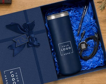 Könnte beinhalten: Eine marineblaue Geschenkbox mit einem passenden marineblauen Becher mit weißem Logo, einem marineblauen Stift und einem schwarzen Ladekabel. Der Deckel hat eine marineblaue Schleife und ein Etikett mit dem Text "YOUR LOGO HERE" aufgedruckt.