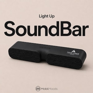 Può includere: Una soundbar rettangolare nera con due sezioni di altoparlanti rivestite in tessuto e un pannello di controllo centrale con cinque pulsanti. La superficie superiore mostra il testo 'YOUR LOGO HERE' e l'immagine include 'Light Up SoundBar' e 'MobilMoods'.
