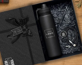 Könnte beinhalten: Eine schwarze Geschenkbox mit einer mattschwarzen Wasserflasche mit dem Text YOUR LOGO HERE, einem schwarzen Stift, einem schwarzen Ladekabel und einem kleinen runden Anhänger mit dem Text YOUR LOGO HERE. Eine schwarze Schleife ziert den Deckel.
