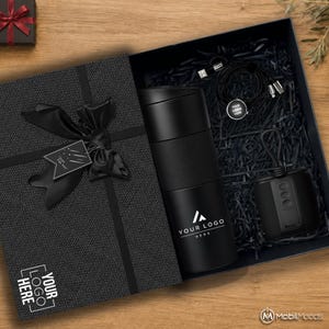 以下が含まれることがあります： YOUR LOGO HEREと書かれた黒いトラベルマグ、円形のタグが付いた黒い充電ケーブル、黒い正方形のスピーカーが入った黒いギフトボックス。箱の蓋には黒いリボンの結び目とJust For Youと書かれたタグが付いています。