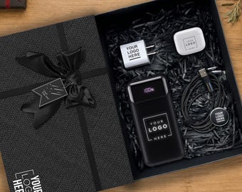 Könnte beinhalten: Eine schwarze Geschenkbox mit einer schwarzen Powerbank mit 100%-Digitalanzeige, einem weißen Wandladegerät, einem weißen Ohrhörer-Etui und einem schwarzen Ladekabel. Jeder Artikel ist mit dem Text YOUR LOGO HERE versehen.