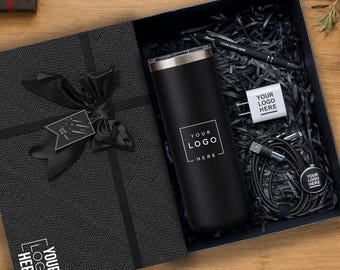 Könnte beinhalten: Eine schwarze Geschenkbox mit einem schwarzen Becher mit dem Text YOUR LOGO HERE, einem schwarzen Stift, einem weißen Netzteil mit dem Text YOUR LOGO HERE und einem schwarzen Ladekabel mit einem runden Anhänger mit dem Text YOUR LOGO HERE.