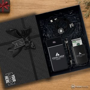 May include: A black gift box containing a power bank with a digital display, a black pen, a card holder with a 100 dollar bill, and a multi-charging cable. The box lid features a black ribbon bow and a tag with the text Just For You.