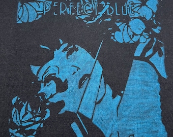 May include: A black and blue iron-on patch with the text "PERFECT BLUE" in white lettering. The patch features a stylized image of a woman's face.