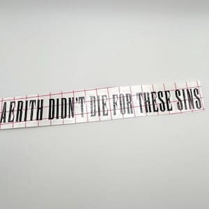 Op de afbeelding: Een witte sticker met zwarte tekst die "Aerith stierf niet voor deze zonden" zegt.