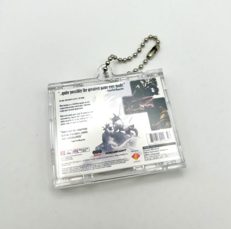 May include: A clear plastic keychain featuring the back of a video game case. The case is for the game "Final Fantasy VII" and has a quote from GameFan Magazine: "quite possibly the greatest game ever made."