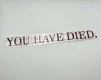 May include: A white sticker with black text that reads "YOU HAVE DIED."