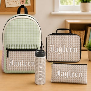 May include: A coordinated set of school supplies, including a backpack, lunch bag, water bottle, and pencil case. Each item has a light green and tan gingham pattern and the name "Jayleen" in a decorative font.