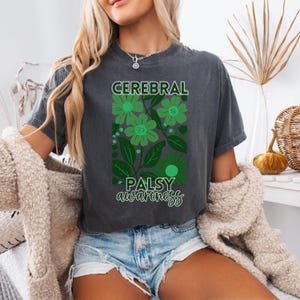 May include: A dark gray t-shirt with a green floral design and the text "Cerebral Palsy awareness".