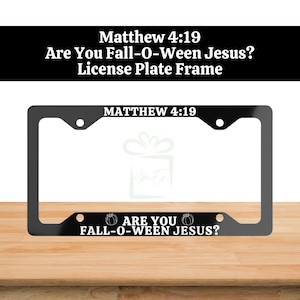 May include: A black rectangular license plate frame featuring white text. The top bar displays the text MATTHEW 4:19. The bottom bar features the text ARE YOU FALL-O-WEEN JESUS? flanked by two small white line-art pumpkin illustrations.