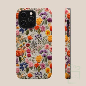 May include: A white phone case with a floral pattern. The flowers are embroidered and are in shades of pink, orange, yellow, and purple. The case has a black camera cutout and a black side.