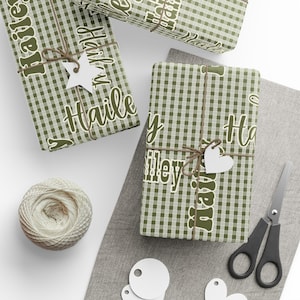 May include: Three wrapped gifts with green and white checkered paper, tied with twine and adorned with white tags. The gifts are labeled "Hailey" in a retro font. A ball of twine, scissors, and blank tags are also present.