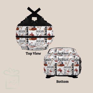 May include: White baseball-themed backpack with black straps. The backpack has a repeating pattern of baseball bats, baseballs, and the name "Jackson". The backpack is shown from the top and bottom.