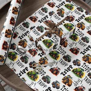 May include: White wrapping paper featuring a repeating pattern of colourful tractors and the name "TRIPP" in black. A wrapped gift box with a brown ribbon and a roll of matching paper are visible.