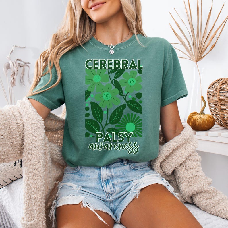May include: A teal green t-shirt with a floral design and the text "Cerebral Palsy awareness".