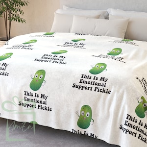 May include: White fleece blanket with a repeating pattern of green cartoon pickles with the text "This is my emotional support pickle".