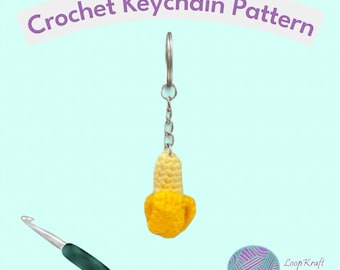 Puede incluir: Un llavero de plátano tejido a ganchillo con una anilla y cadena de metal plateado, acompañado de un ganchillo con mango verde oscuro. El texto Crochet Keychain Pattern aparece arriba y un icono de ovillo con el texto Loop Kraft está abajo.