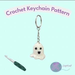May include: A white crocheted ghost keychain with black eyes and a black mouth, attached to a silver metal ring and chain. A green crochet hook and a ball of yarn are visible. The text Crochet Keychain Pattern and Loop Kraft are present.