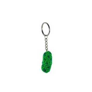 Puede incluir: Un llavero de pepinillo tejido en verde con un anillo de metal plateado.