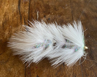May include: White fly fishing lure with iridescent feathers and a green body.
