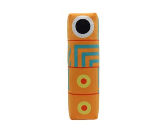 May include: A plush toy shaped like a tall, thin, orange and blue geometric figure with a black eye and yellow and red circles.