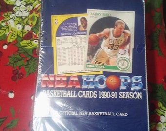 May include: A sealed box of 1990-91 NBA Hoops basketball cards featuring Larry Bird and Earvin Johnson on the front. The box is blue with white text and a basketball graphic.