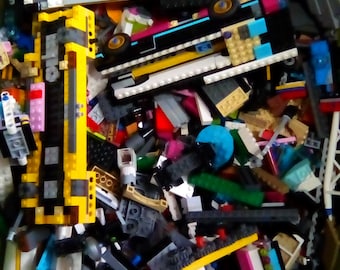 May include: A large bin filled with a variety of colorful Lego bricks, including yellow, blue, red, green, and black. The bricks are in various shapes and sizes, and some are assembled into small structures.