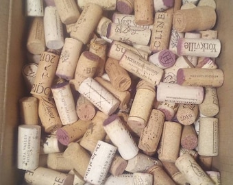 May include: A box filled with a variety of wine corks. The corks are made of natural cork and have different labels and markings. Some of the corks have the year 2019 printed on them.