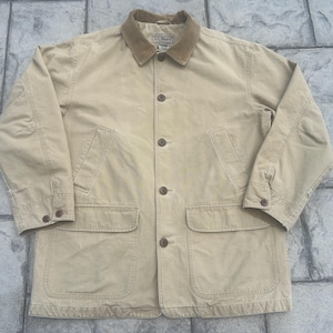 May include: A tan L.L.Bean field jacket featuring a brown corduroy collar, a button-front closure, two large lower patch pockets, and two slanted chest pockets. The long sleeves have buttoned cuffs, and the jacket has a structured, durable design.