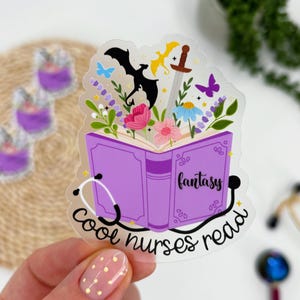May include: A clear sticker featuring a purple book with the word "fantasy" on the cover. The book is open, revealing flowers, butterflies, and a sword. The text "cool nurses read" is written around a stethoscope.