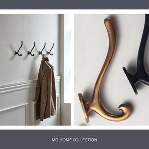 May include: The image presents coat hooks. On the left, four black metal hooks are fixed to a white wall, with a tan blazer hanging from one. To the right, two individual hooks are shown: one with a bronze finish and the other in black.