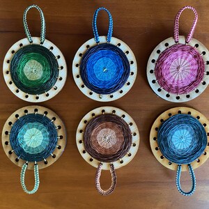 May include: Six round, woven ornaments with different coloured patterns. Each ornament has a loop at the top for hanging.