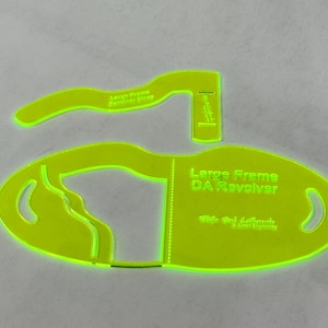 May include: Two neon green quilting templates. One is an oval shape with the text "Large Frame DA Revolver" and the other is a curved shape with the text "Large Frame Revolver Strap".
