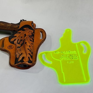 May include: A brown leather holster with a leaf design and a black border, holding a handgun with a wooden grip. A neon green holster template is next to it.