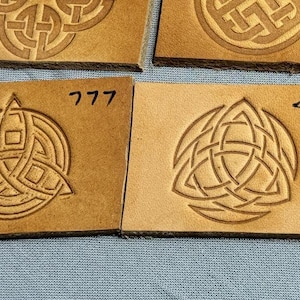 Può includere: Quattro quadrati di pelle con disegni di nodi celtici. I quadrati sono etichettati con i numeri 777 e 44.