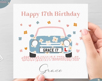 May include: A light blue car with white flowers on it. The car has a pink roof and a license plate that says "GRACE 17". The car is on a pink and white background with hearts and flowers. The text "Happy 17th Birthday" is at the top of the card and the name "Grace" is at the bottom.