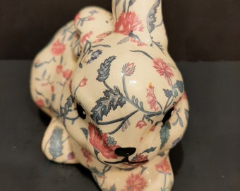 May include: A ceramic bunny figurine with a white base and a floral pattern in shades of pink, blue, and green.