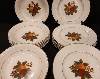 May include: Set of white ceramic dinner plates and bowls with a gold rim and a fruit design. The fruit design features oranges, apples, and leaves in shades of red, orange, green, and brown.