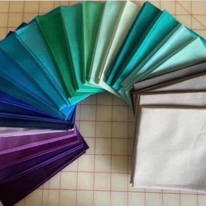 May include: A collection of fabric swatches in various shades of blue, green, purple, and gray arranged in a semi-circle.