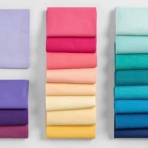 May include: A stack of 10 fabric squares in various shades of blue, a stack of 9 fabric squares in various shades of yellow, and a stack of 8 fabric squares in various shades of pink and purple.
