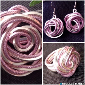 Könnte beinhalten: Ein Set aus silbernem und rosafarbenem Schmuck mit einem Ring und einem Paar Ohrringen. Der Schmuck besteht aus Draht, der zu einer rosenartigen Form gedreht und verknotet ist.