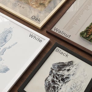 four framed artworks, each with a different color and style, arranged on a wooden surface.