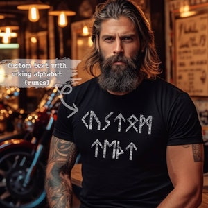 Puede incluir: Una camiseta negra con un dise&ntilde;o blanco de la palabra "CUSTOM" escrita en el alfabeto vikingo (runas).