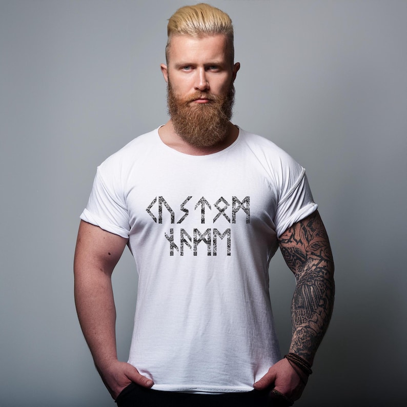 Puede incluir: Camiseta blanca con un gr&aacute;fico negro de la palabra "CUSTOM" escrita en runas.