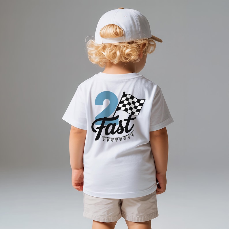 A young child with blonde curly hair wearing a white t-shirt with a graphic design and text on the back.